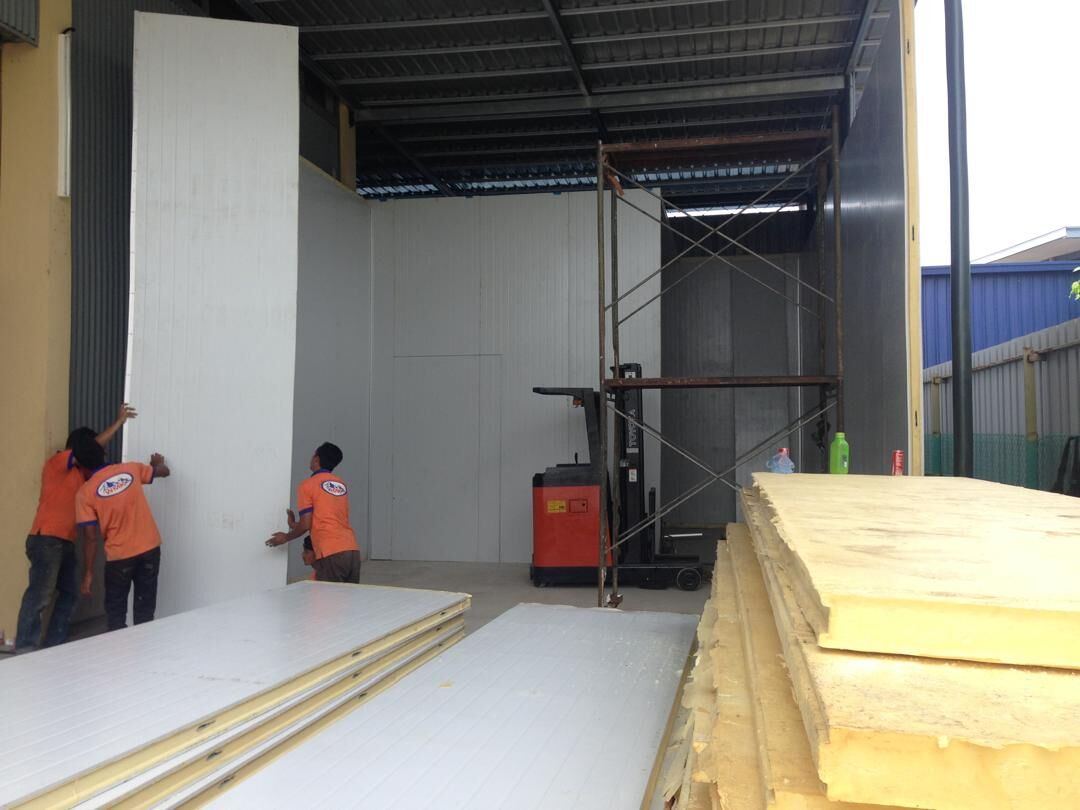 Workers fitting white insulated cold room panels